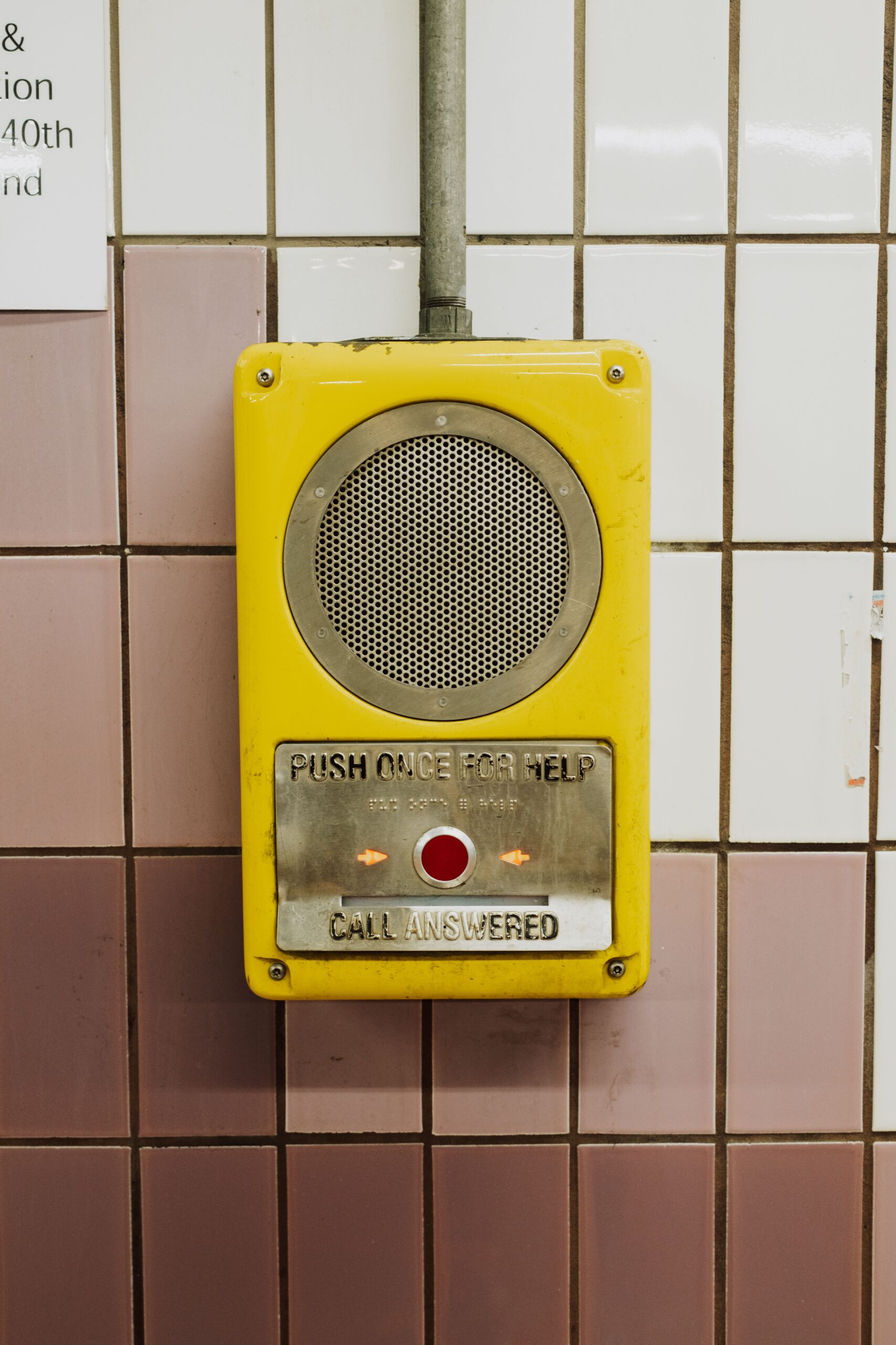 pexels-kelly-28775010 - Living Future Yellow emergency call button with speaker grill mounted on tiled wall, reads'Push once for help' and 'Call answered' nearby